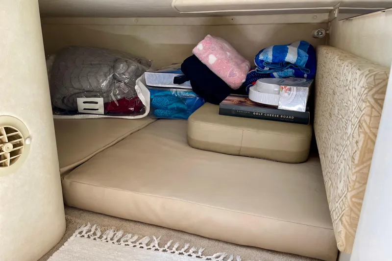 Storage area in a 2000 Monterey 302 Cruiser with cushions and assorted items.