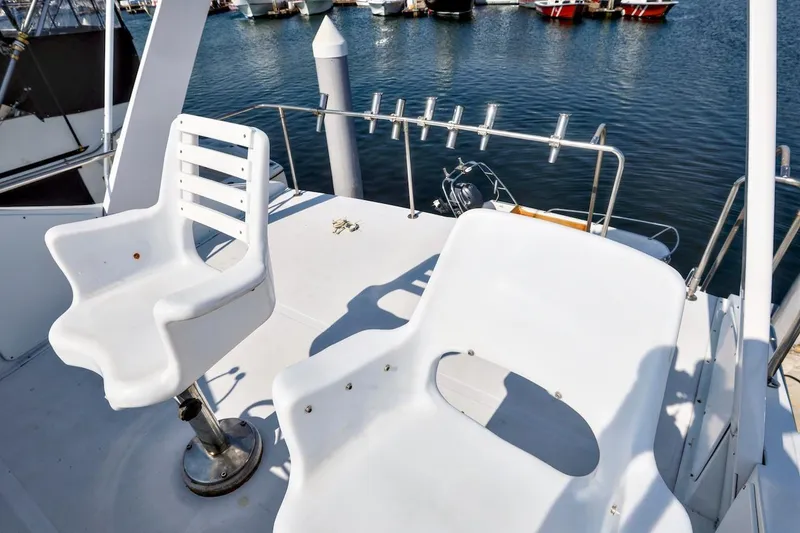 1980 Pacifica 41 Sportfisher boat deck with white chairs and fishing rod holders.