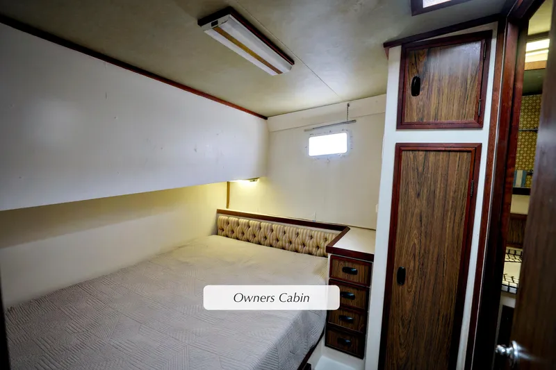 Owner's cabin in 1980 Pacifica 41 Sportfisher, featuring cozy bed and wooden cabinetry.