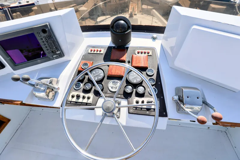 Control panel of a 1980 Pacifica 41 Sportfisher boat with steering wheel and navigation instruments.