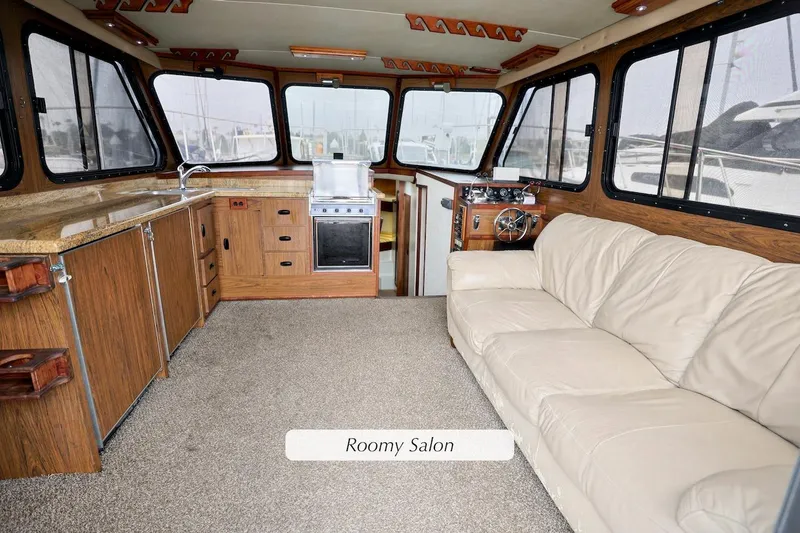 Roomy salon interior of 1980 Pacifica 41 Sportfisher with beige sofa and wooden cabinetry.