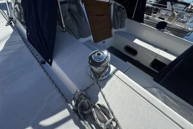 Sailboat deck of 2000 Catalina 320 with winch and ropes in marina setting.