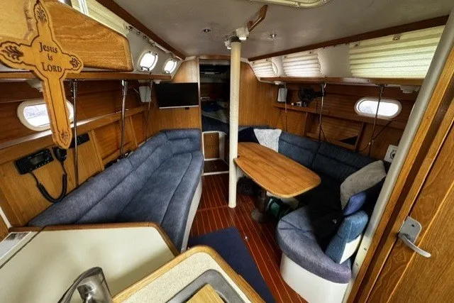 Interior of a 2000 Catalina 320 sailboat with cozy seating and wooden accents.
