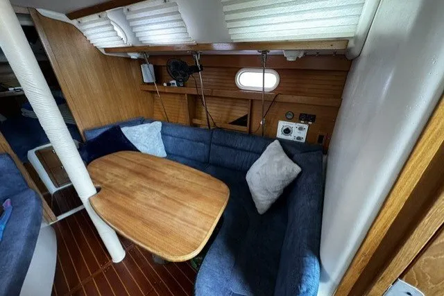 Cozy interior of a 2000 Catalina 320 sailboat with blue seating and wooden table.