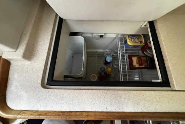 Refrigerator inside a 2000 Catalina 320 yacht, stocked with drinks and food items.