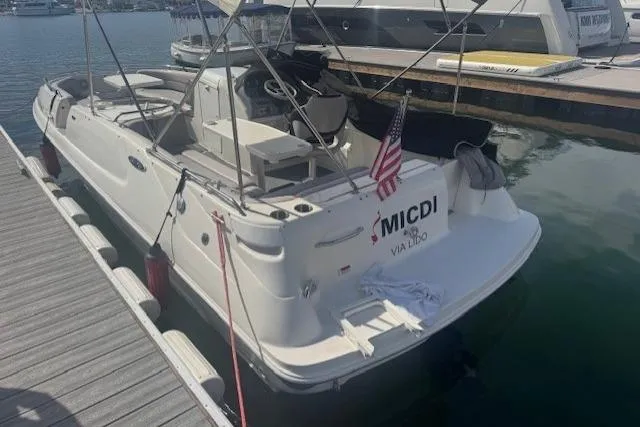 1997 Sea Ray 240 Sundeck docked, featuring a white exterior and American flag.