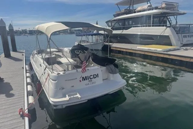 1997 Sea Ray 240 Sundeck docked at marina, featuring canopy and American flag.
