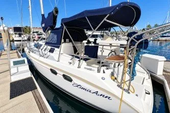 Hunter 376 sailboat, 1996 model, docked at marina with blue canopy and clear skies.
