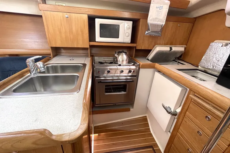 Compact kitchen in 2004 Catalina 350 sailboat with stove, sink, and microwave.
