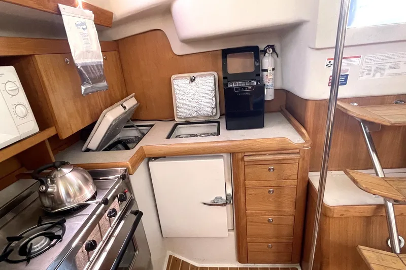 2004 Catalina 350 yacht kitchen with stove, kettle, and wooden cabinetry.