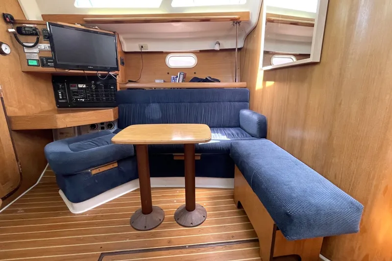 Interior of a 2004 Catalina 350 sailboat with blue seating and wooden table.