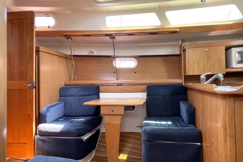 Interior of a 2004 Catalina 350 sailboat with wooden cabinetry and blue seating.