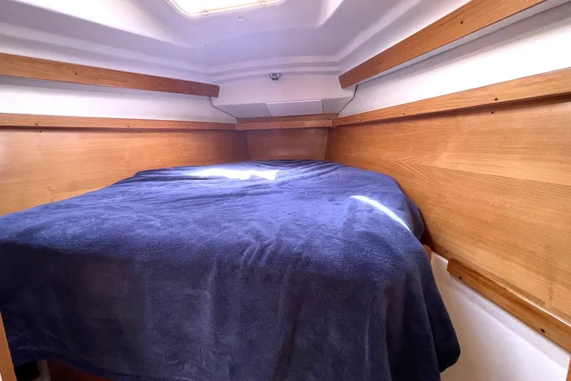 Cozy cabin interior of 2004 Catalina 350 sailboat with wooden accents and blue bedding.
