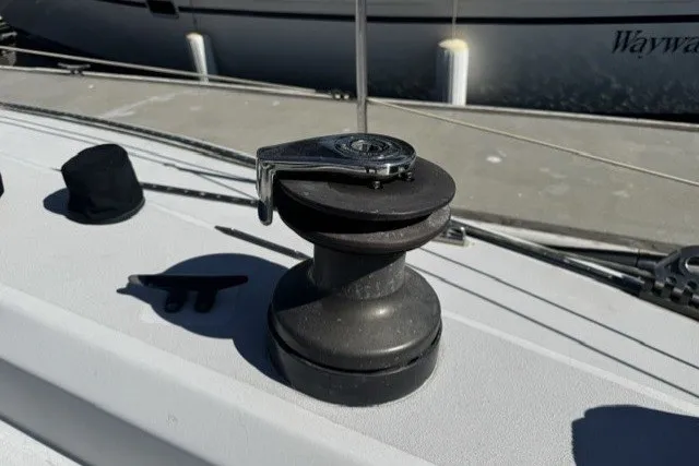 Winch on deck of 1973 Custom BILL LEE 40 sailboat, with marina background.