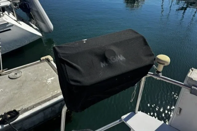 Covered grill on a 1973 Custom BILL LEE 40 sailboat docked by the water.