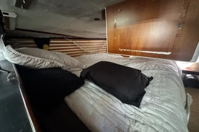 Cozy cabin interior of 1973 Custom BILL LEE 40 sailboat with bedding and wooden paneling.