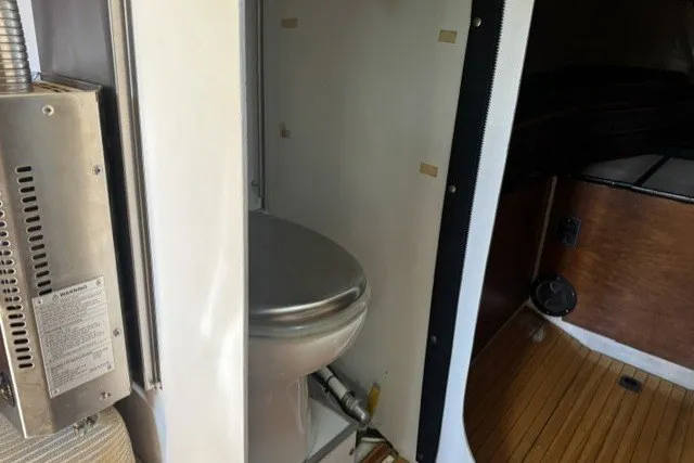 Interior of a 1973 Custom BILL LEE 40 yacht featuring a compact bathroom with a stainless steel toilet.