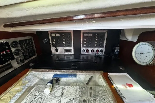 Navigation station of a 1973 Custom BILL LEE 40 sailboat with charts and instruments.