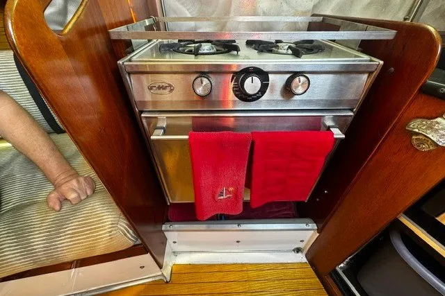 Vintage 1973 Custom BILL LEE 40 yacht stove with red towels in cozy cabin setting.