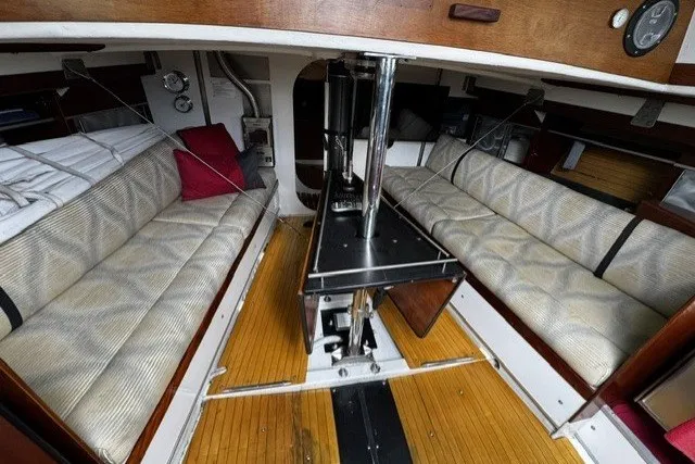 Interior of 1973 Custom BILL LEE 40 sailboat with cozy seating and wooden flooring.