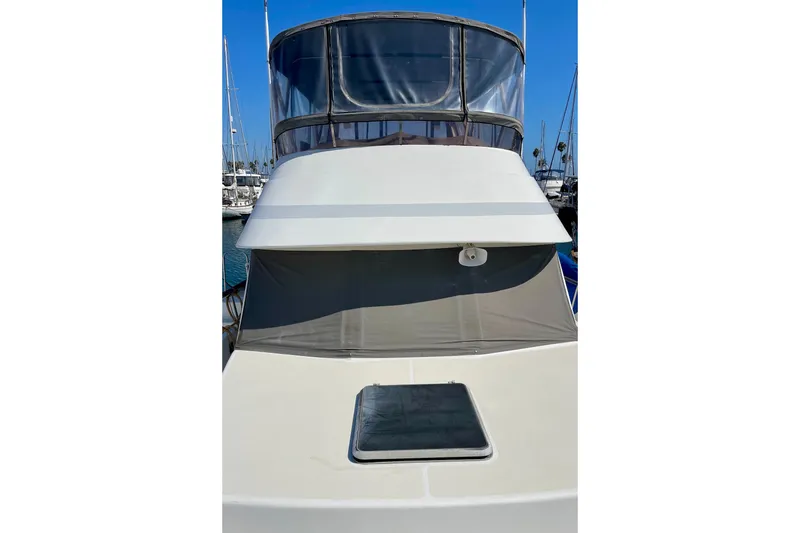 1985 CHB 42 yacht with flybridge, docked in marina under clear blue sky.