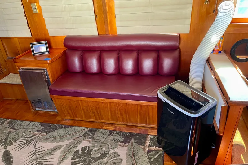 Interior of a 1985 CHB 42 boat with maroon seating and portable air conditioner.