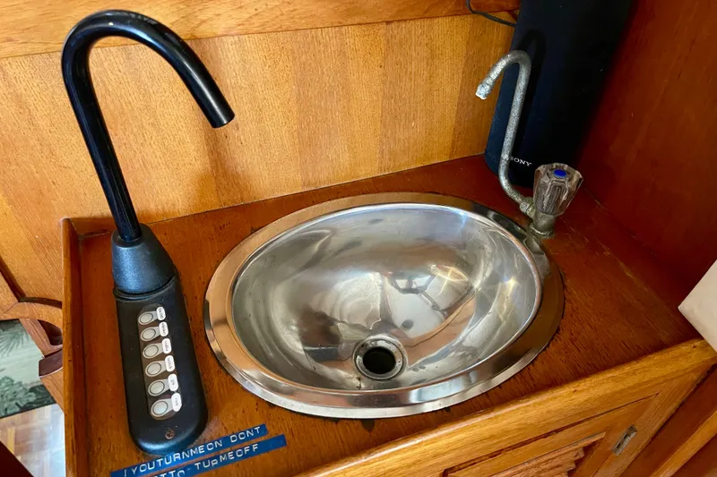 1985 CHB 42 boat sink with faucet and control panel on wooden countertop.