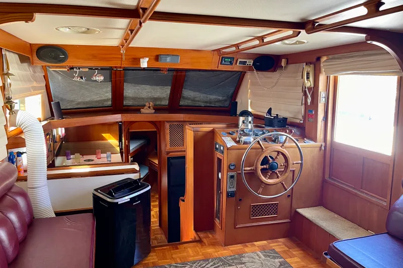 Interior of a 1985 CHB 42 boat with wooden helm and cozy seating area.