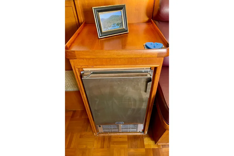 Wooden interior of 1985 CHB 42 boat with a compact fridge and framed photo.