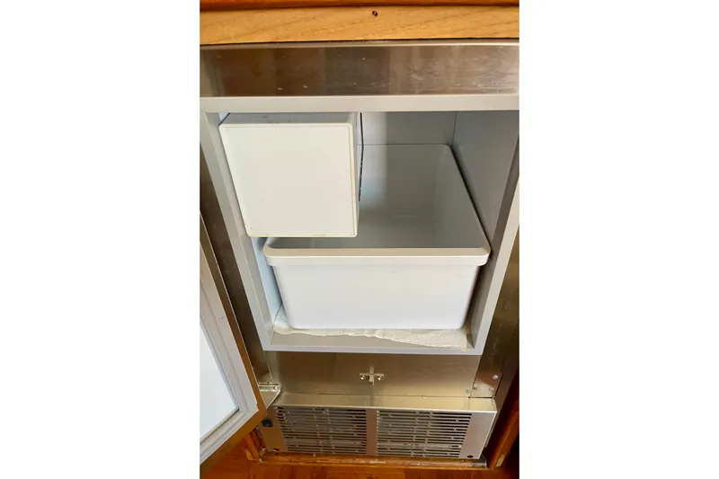 Open refrigerator compartment on a 1985 CHB 42 boat, featuring a white storage bin.