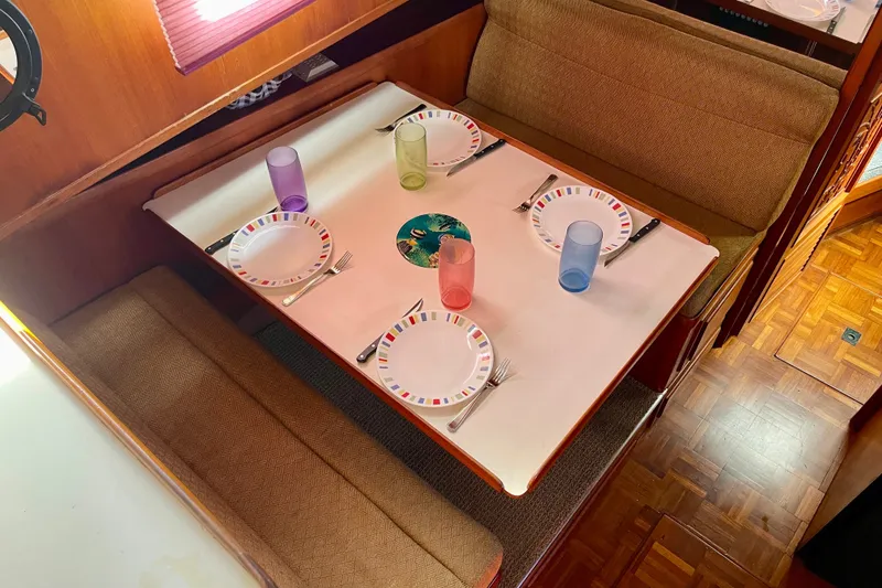 Dining area in a 1985 CHB 42 boat with set table and colorful glasses.
