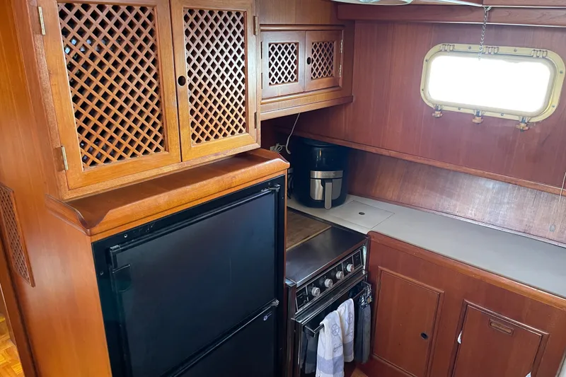1985 CHB 42 boat kitchen with wooden cabinets, stove, and window.