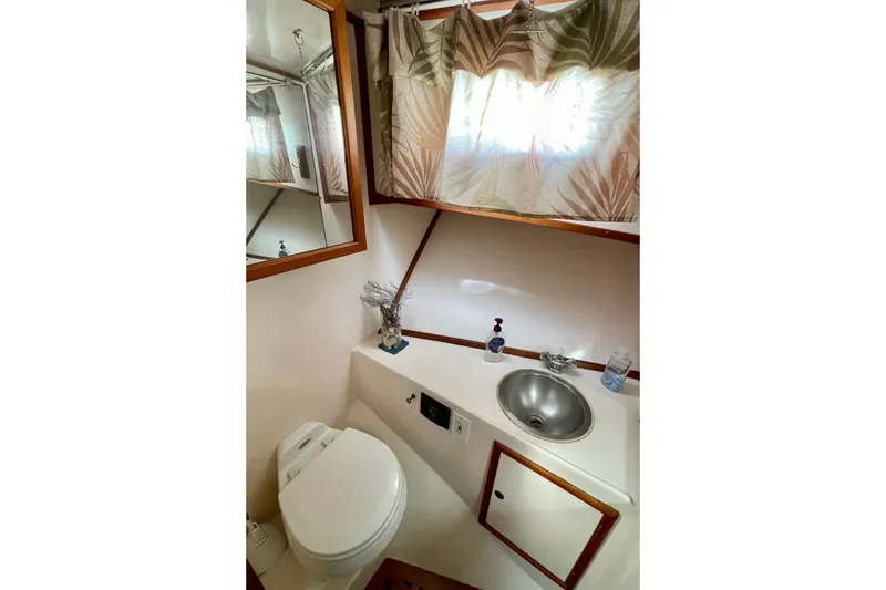1985 CHB 42 yacht bathroom with sink, toilet, mirror, and tropical curtains.