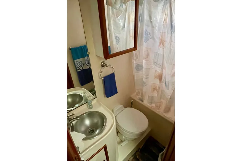 Compact bathroom in a 1985 CHB 42 boat with sink, toilet, and shower curtain.