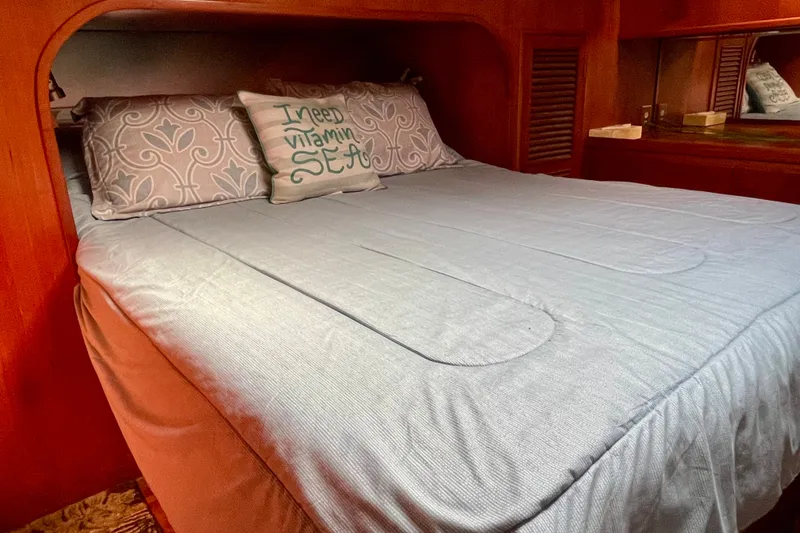 Cozy bedroom in 1985 CHB 42 boat with decorative pillows and wooden interior.