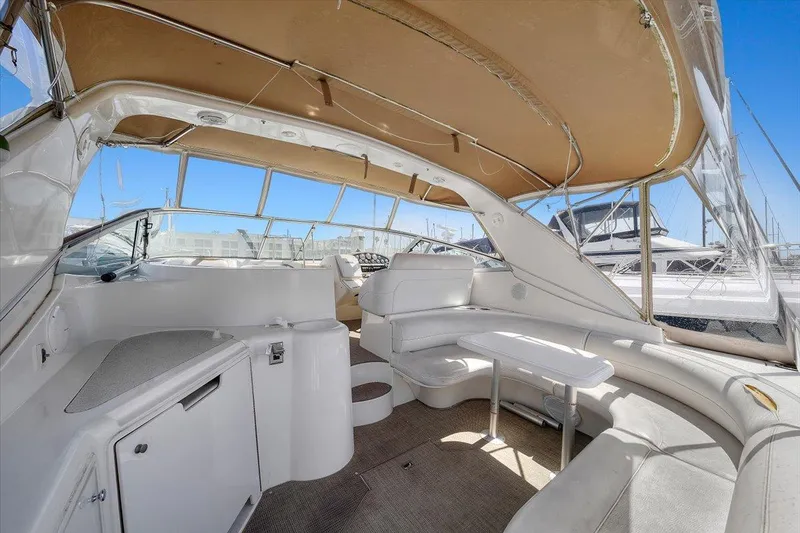 1999 Cruisers Yachts 3870 Esprit interior with white seating and helm, under tan canopy.
