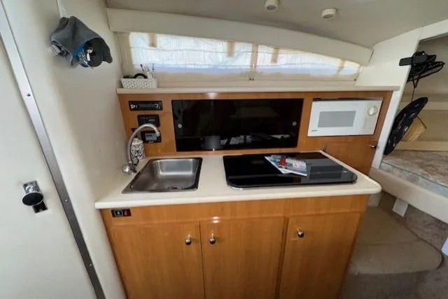 2001 Bayliner 2855 Ciera boat interior kitchen with sink, stove, and microwave.